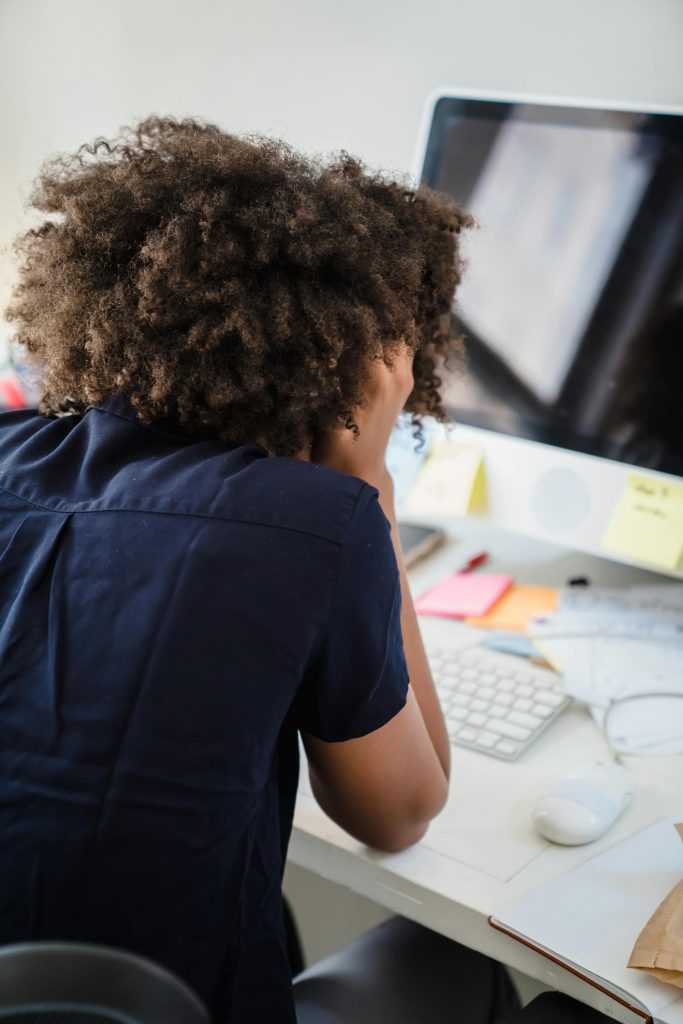 Woman sitting at her desk frustrated with her face in her hands, blocked creatively